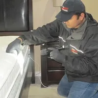 Bed bug inspection technician checking a mattress and bed frame for signs of infestation in Stamford, CT