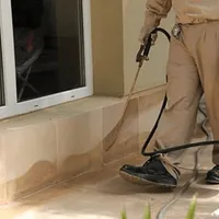 General pest control technician spraying exterior perimeter around a home in Stamford, CT
